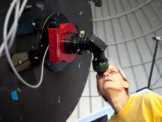 Prof. Carol Schwalbe looks through a telescope.